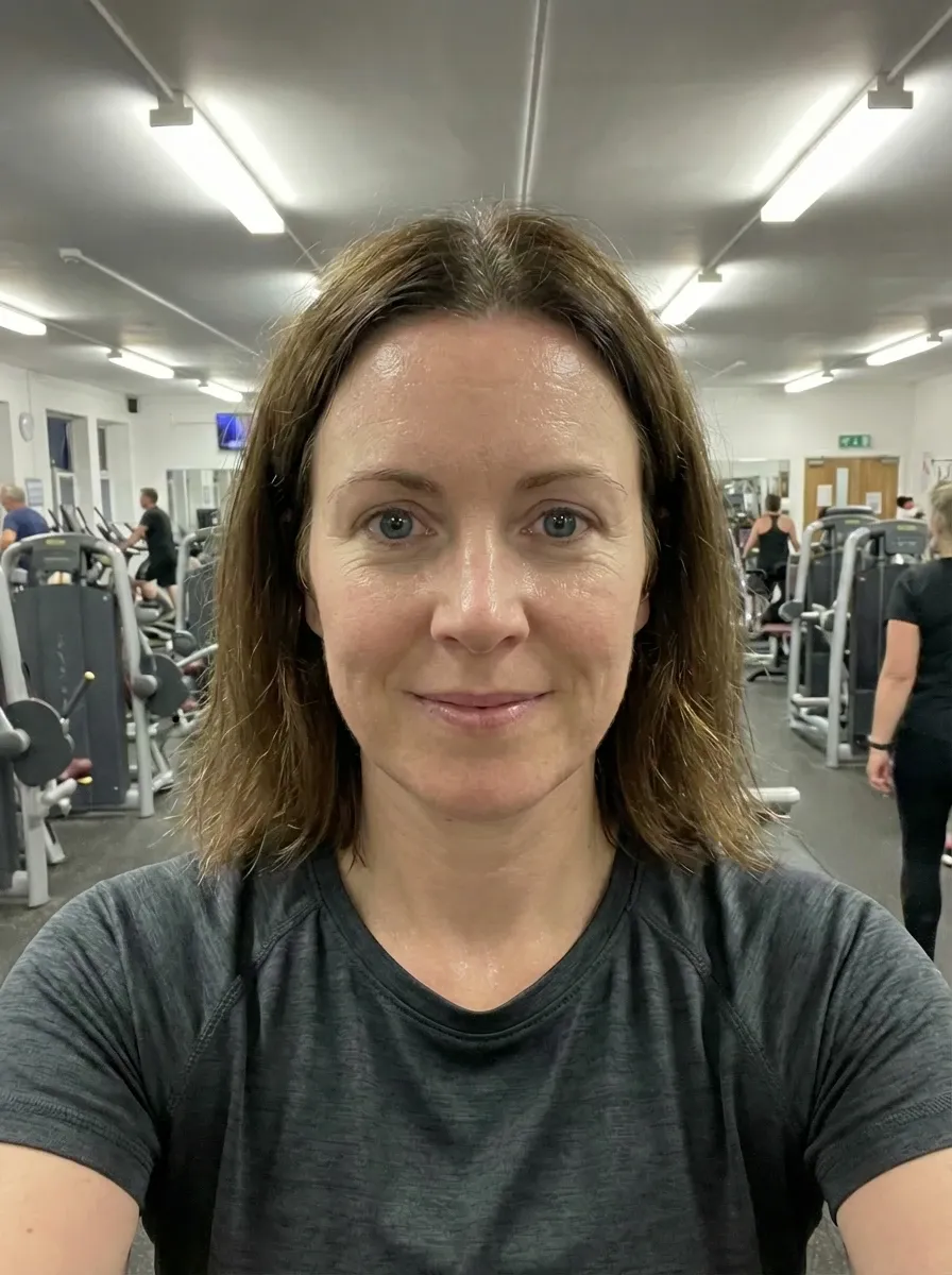 Gym selfie of a woman in a dark gray athletic T-shirt